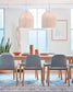 Lámparas colgantes de mimbre sobre mesa de comedor moderna con sillas grises, decoración minimalista.