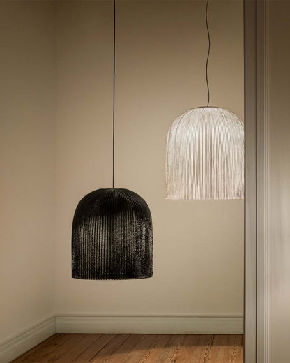Lámparas colgantes modernas de gran tamaño en sala minimalista con luz suave y piso de madera.