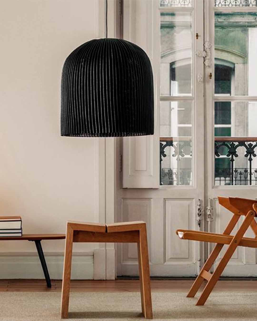 Lámpara colgante negra moderna en sala con muebles de madera y luz natural