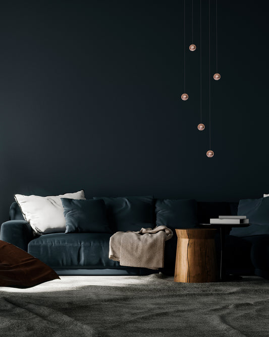 Sala moderna con sofá azul, mesa auxiliar de madera y lámparas colgantes de diseño.