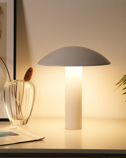 Lámpara de mesa moderna blanca encendida sobre escritorio con jarrón decorativo y planta