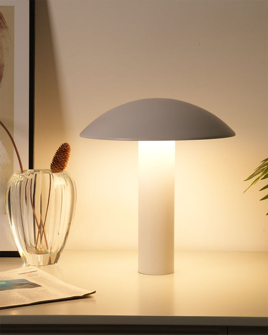 Lámpara de mesa moderna blanca encendida sobre escritorio con jarrón decorativo y planta