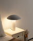 Lámpara de mesa moderna blanca sobre buró en dormitorio minimalista, iluminación cálida