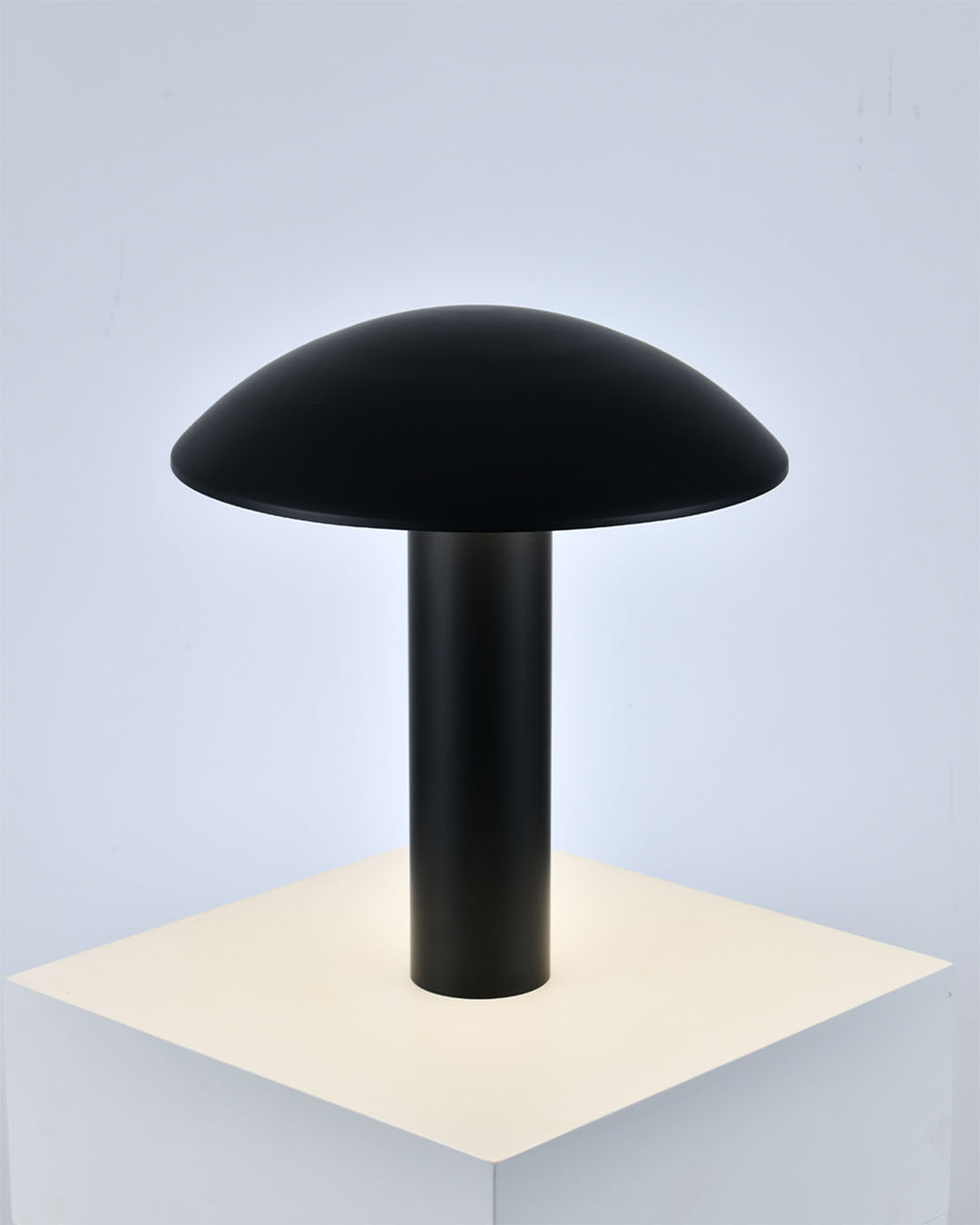 Lámpara de mesa negra de diseño minimalista sobre base blanca en ambiente moderno
