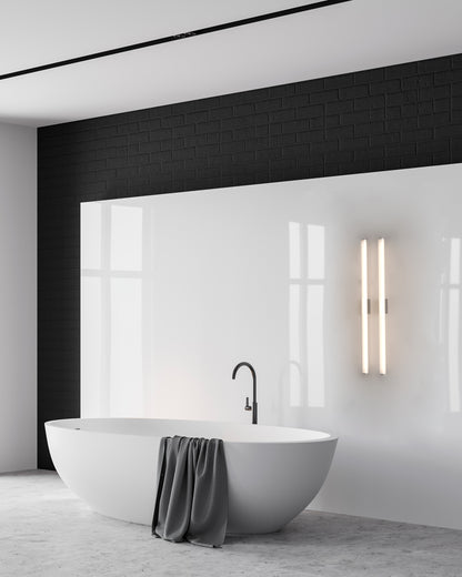Lámpara de pared moderna en baño minimalista con tina blanca y pared de azulejos negros