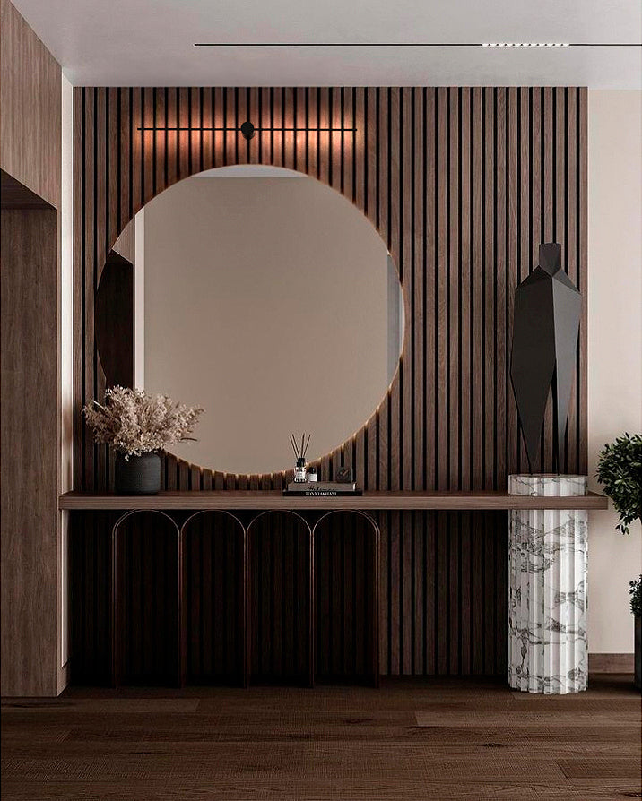 Recibidor moderno con espejo redondo, mesa de madera, luz decorativa y detalles de mármol.