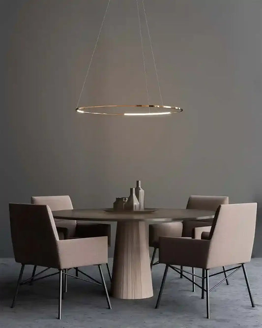 Lámpara colgante LED dorada sobre mesa redonda con cuatro sillas en ambiente moderno