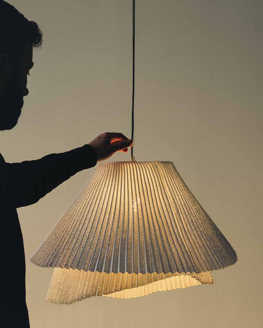 Lámpara colgante de diseño plisado encendida en ambiente moderno, iluminación decorativa.