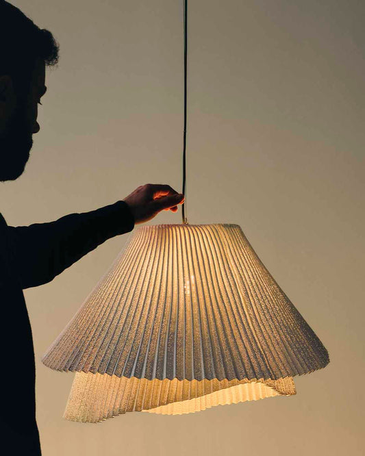 Lámpara colgante de diseño plisado encendida en ambiente moderno, iluminación decorativa.