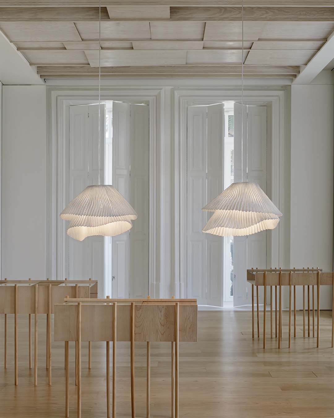 Lámparas colgantes de diseño moderno en sala minimalista con muebles de madera clara.