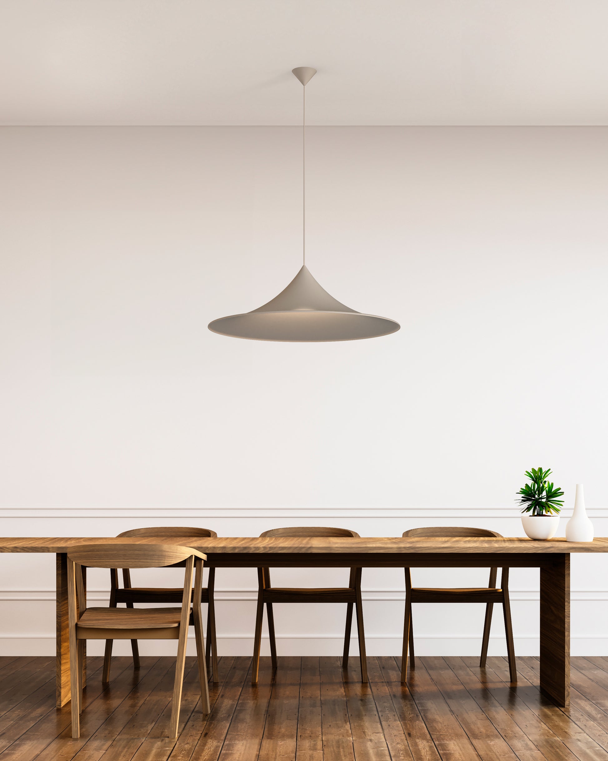 Lámpara colgante moderna sobre mesa de madera en comedor minimalista con sillas y planta decorativa.
