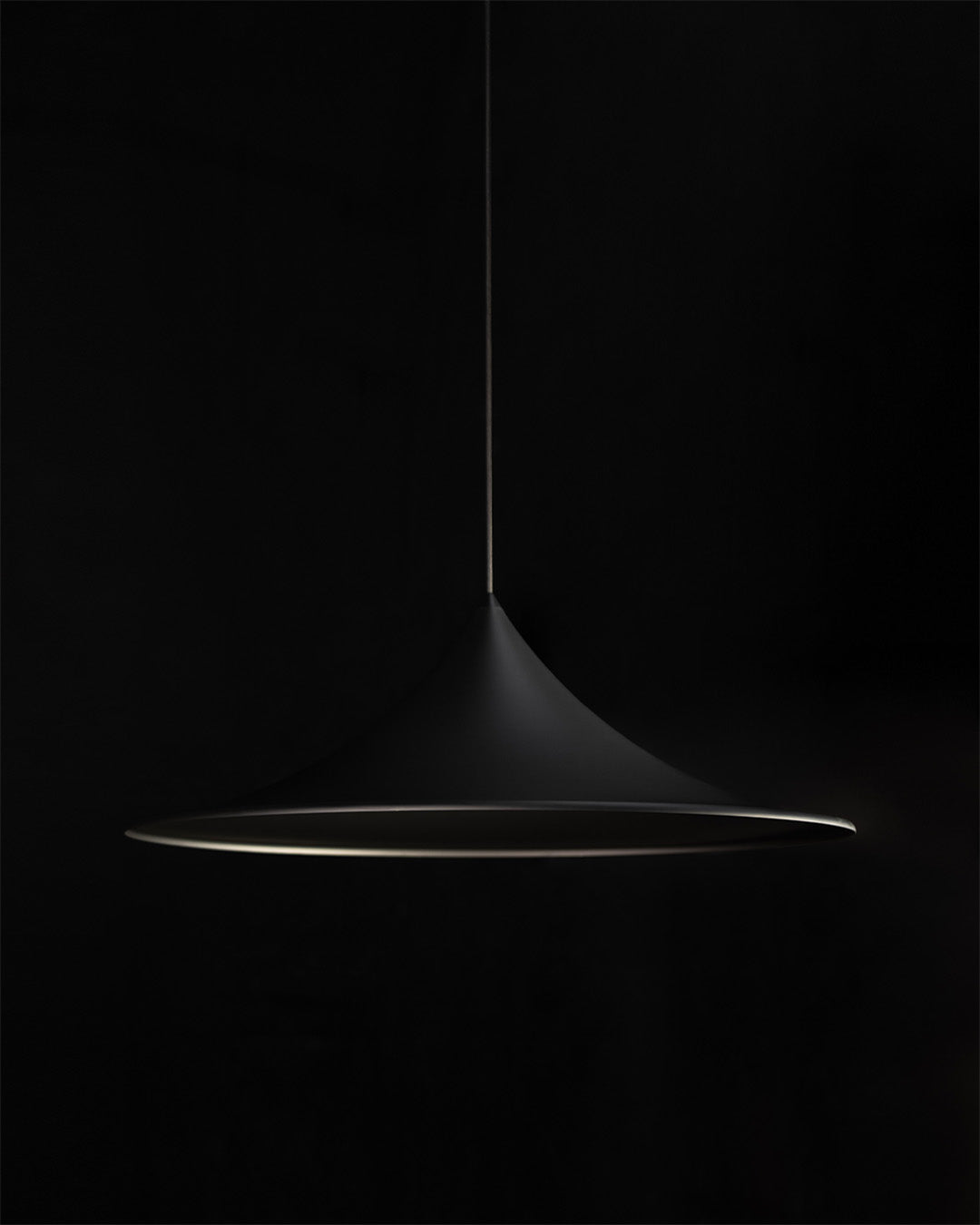 Lámpara colgante negra de diseño moderno sobre fondo oscuro, iluminación decorativa.