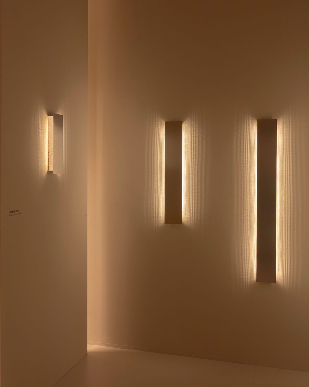 Apliques de pared modernos verticales iluminando pared beige, iluminación decorativa interior.