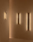 Apliques de pared modernos verticales iluminando pared beige, iluminación decorativa interior.