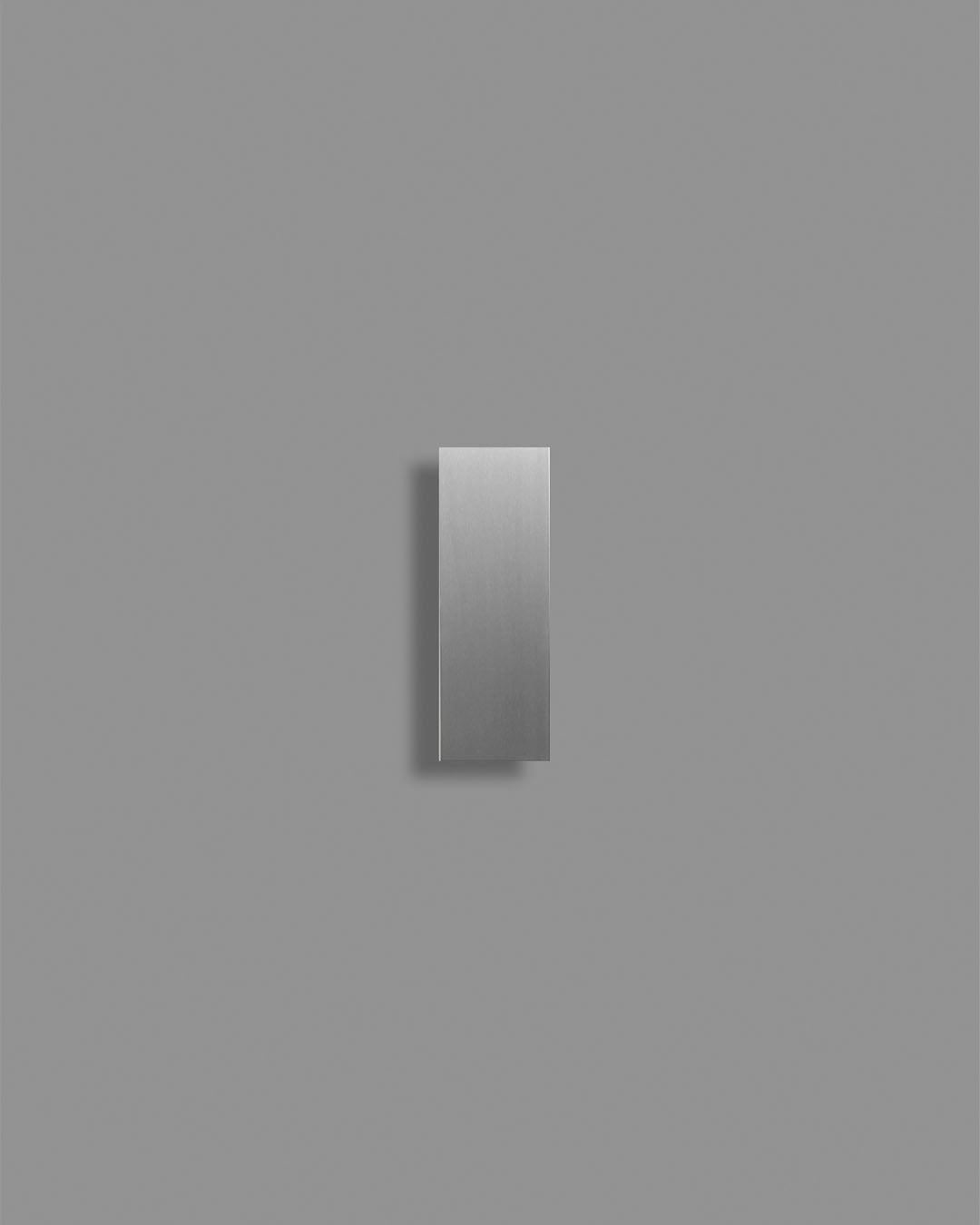 Aplique de pared moderno en acero inoxidable, diseño minimalista sobre fondo gris.