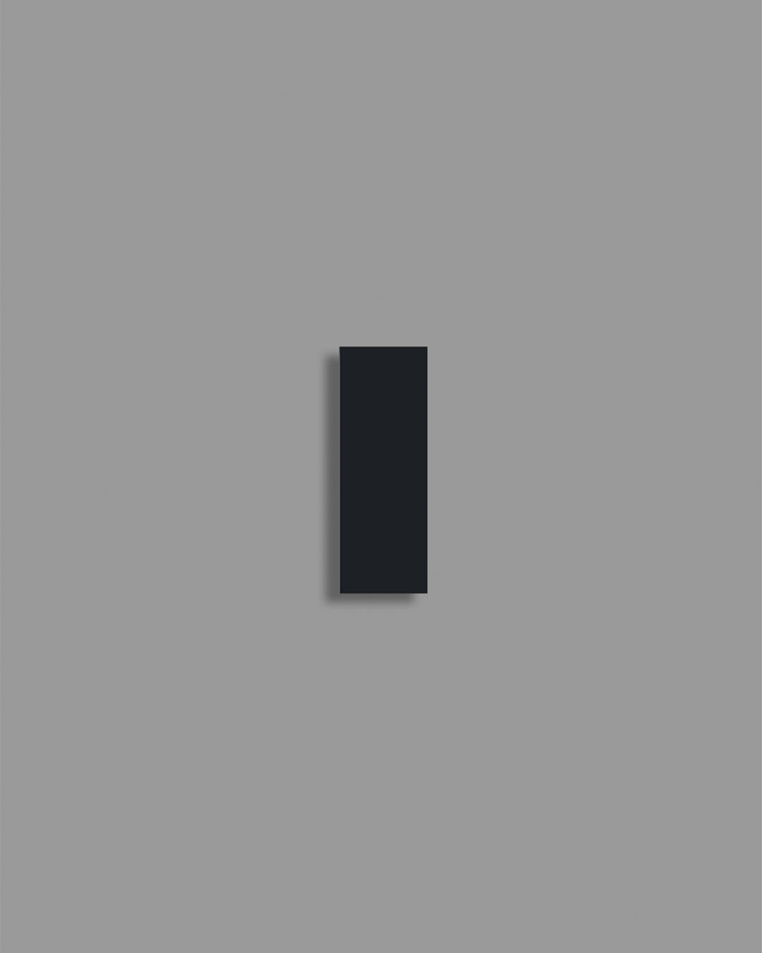 Aplique de pared moderno rectangular negro sobre fondo gris, iluminación minimalista.