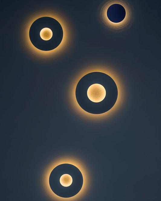 Aplique de pared escultural minimalista Umbra Round en malla de acero con luz indirecta concéntrica.