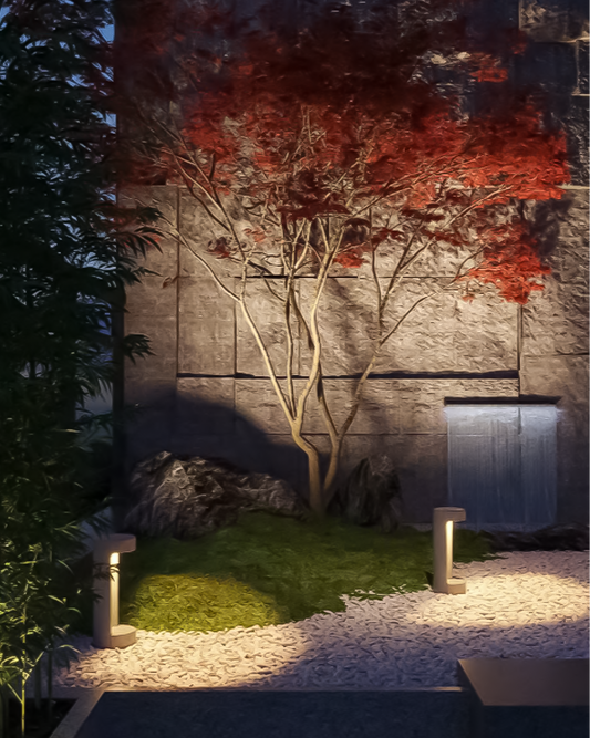 Luminarias de jardín exteriores iluminando sendero con árbol y piedras decorativas.