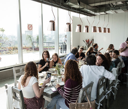 Lámparas colgantes modernas de cobre sobre mesa con personas en restaurante luminoso