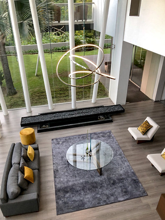 Sala moderna con lámpara colgante de diseño, ventanales grandes y muebles minimalistas