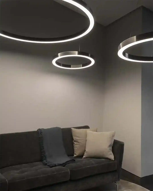 Lámparas circulares modernas de techo iluminando sala con sofá gris, Birot MX boutique de iluminación.
