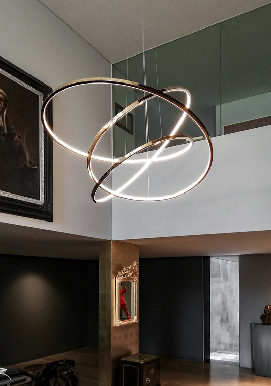 Lámpara colgante LED moderna de aros dorados en sala contemporánea con arte decorativo.