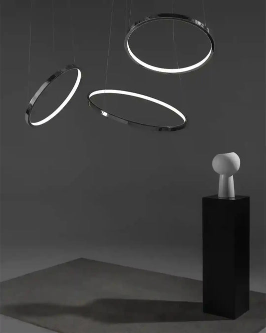Aros colgantes LED modernos sobre pedestal en ambiente minimalista, iluminación decorativa Birot MX