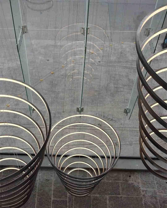 Lámpara colgante de aros modernos en boutique de iluminación Birot MX, frente a vidrio y piso gris.