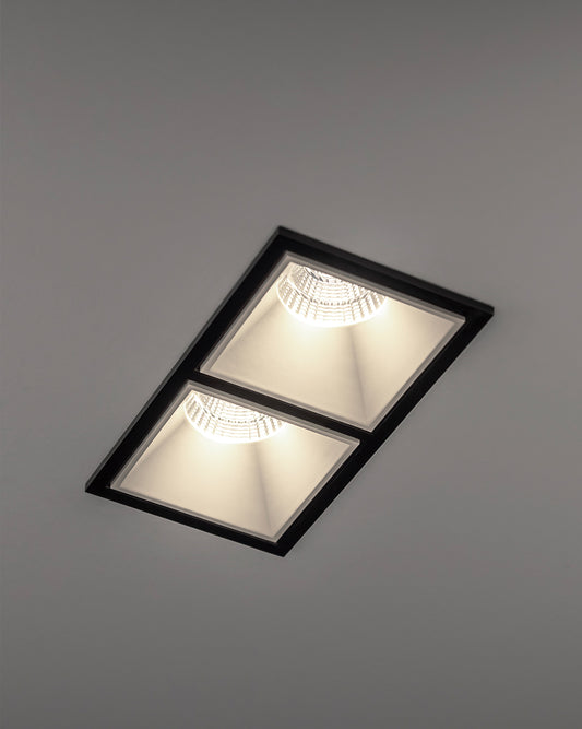 Luminaria empotrada de techo negra con dos focos LED encendidos, diseño moderno.