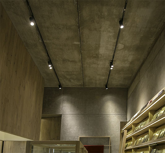 Rieles de focos LED para iluminación interior en techo de concreto, estilo moderno.
