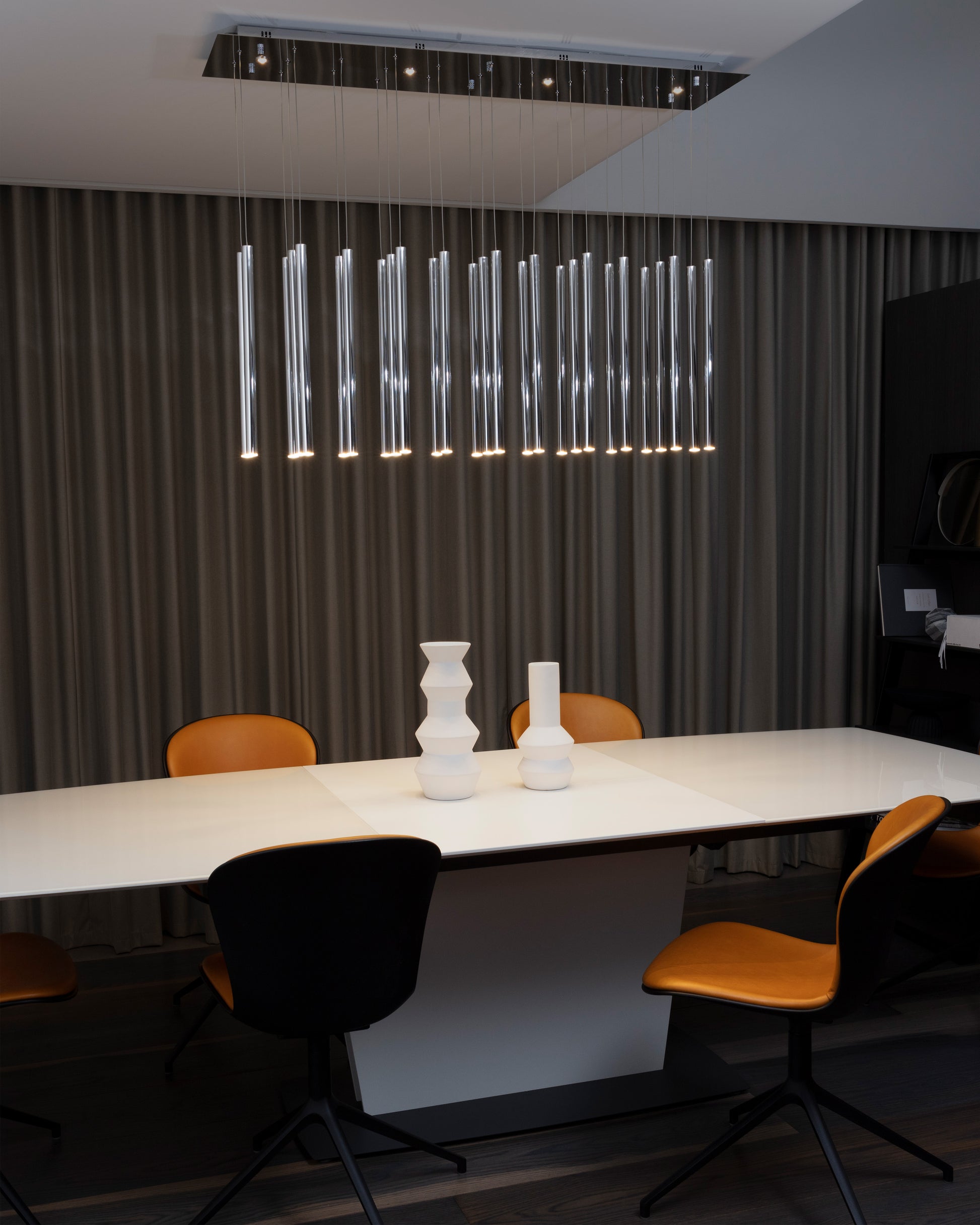 Lámpara colgante moderna sobre mesa blanca con sillas mostaza y decoración minimalista