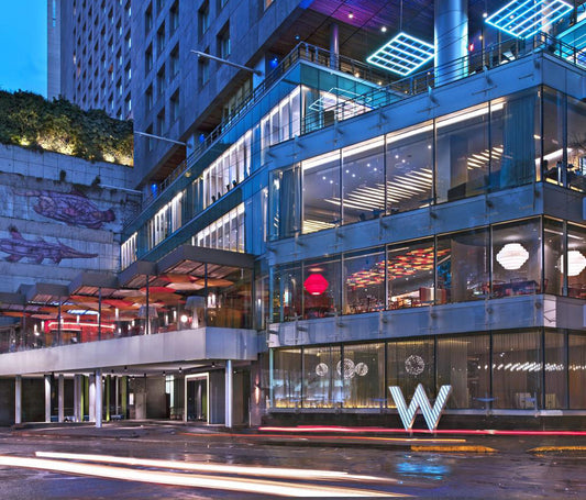 Fachada moderna de hotel con grandes ventanales y luminarias decorativas exteriores
