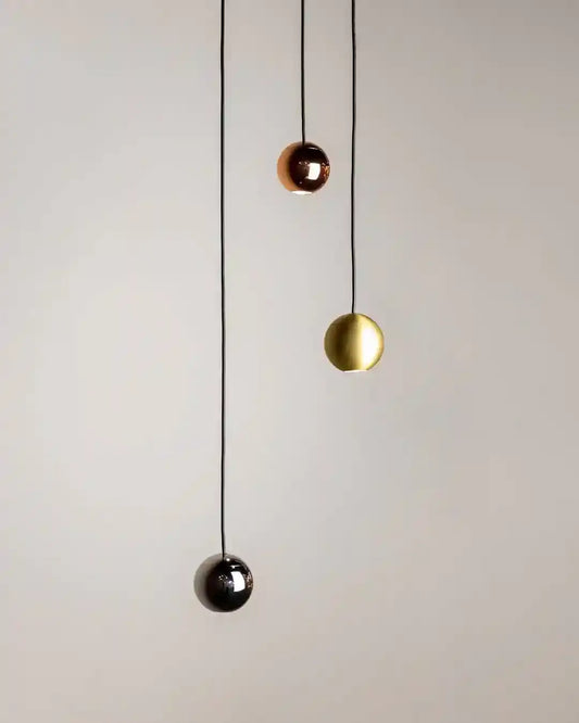 Lámparas colgantes esféricas en dorado, cobre y negro sobre fondo beige, Birot MX iluminación