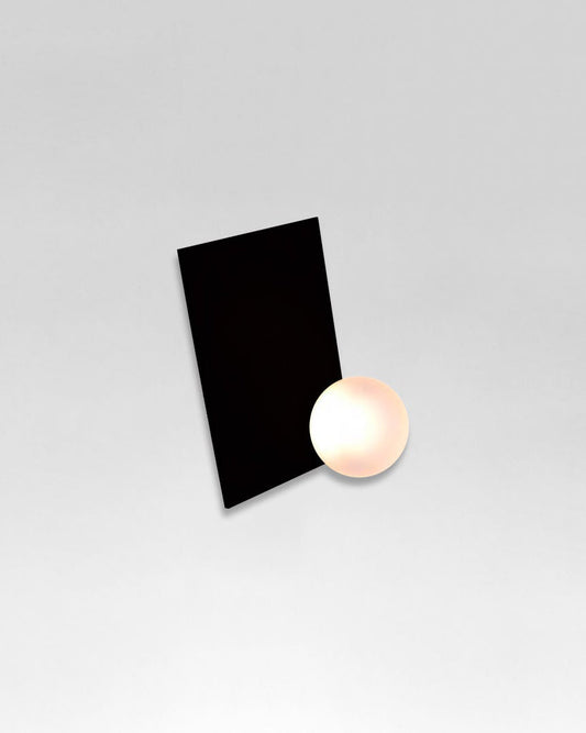 Aplique de pared negro moderno con esfera blanca iluminada sobre fondo gris