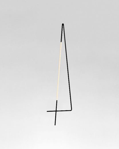 Lámpara de pie minimalista negra y dorada sobre fondo gris, iluminación moderna.