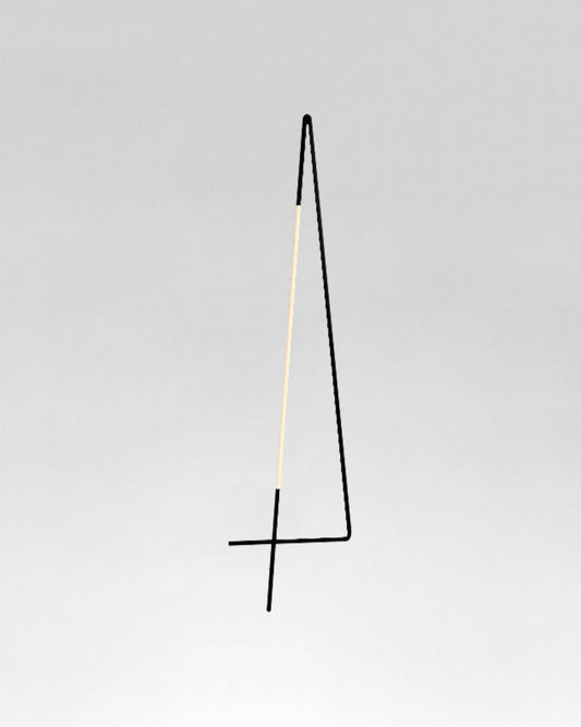 Lámpara de pie minimalista negra y dorada sobre fondo gris, iluminación moderna.