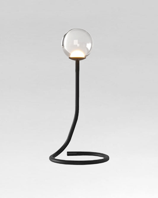 Lámpara de mesa moderna con base curva negra y esfera de vidrio transparente decorativa.
