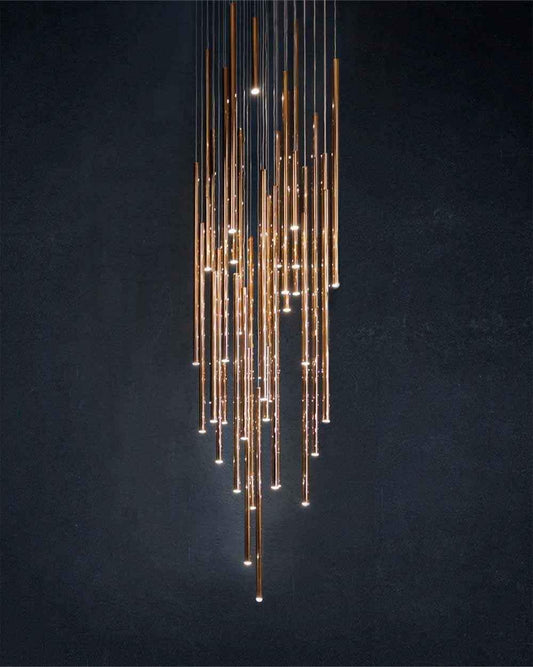 Lámpara colgante moderna de tubos dorados encendidos en fondo oscuro, boutique Birot MX.