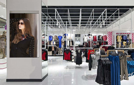 Tienda de ropa moderna con exhibidores de prendas y cartel de modelo con gafas de sol
