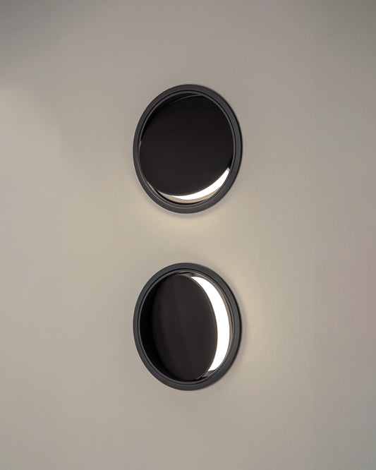 Dos apliques de pared circulares negros con luz LED moderna en interior minimalista