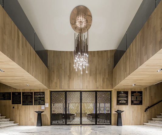 Lámpara colgante moderna en vestíbulo con paredes de madera y puertas decorativas.