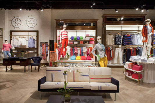 Tienda boutique de moda con maniquíes y ropa colorida exhibida en estantes y mesas.